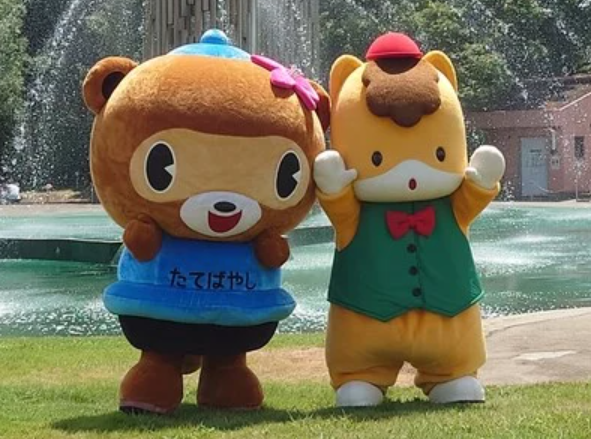Tatebayashi City mascot Pon-chan and Gunma-chan mascots in front of a fountain.