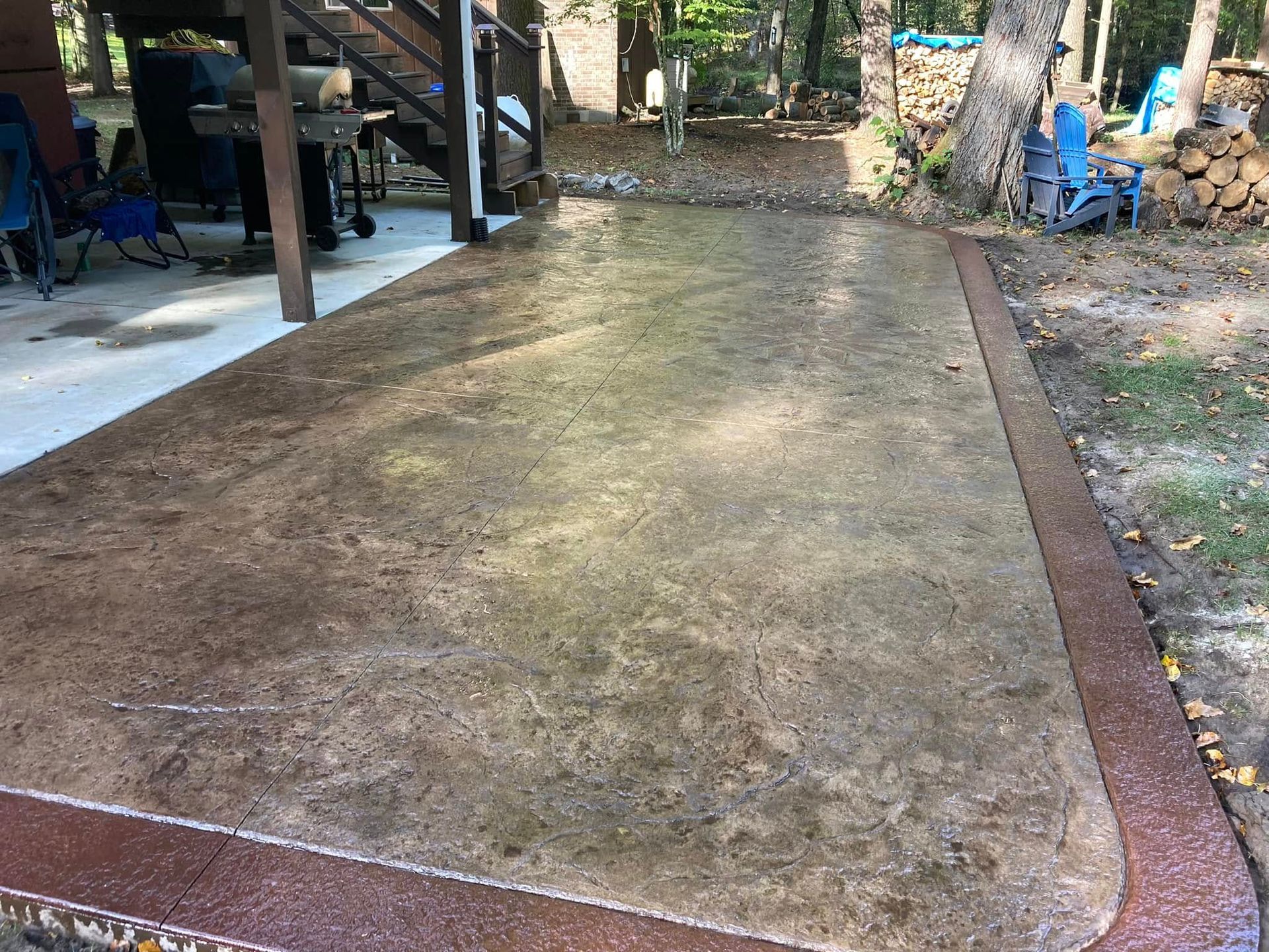 A concrete patio with a staircase and chairs in the background.