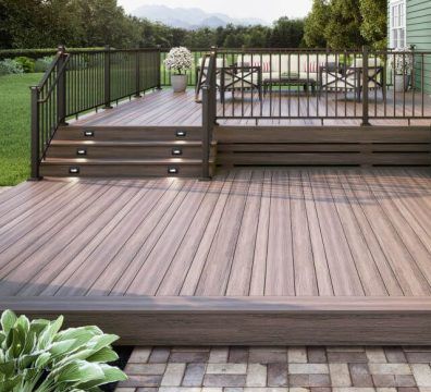 Wooden deck with railing, steps, and outdoor furniture in a backyard setting.