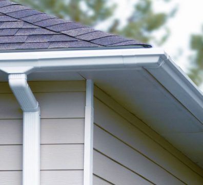 White gutters on a beige house with a dark roof.