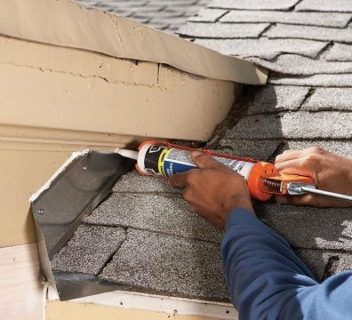 Person applying sealant to a roof near an eave.
