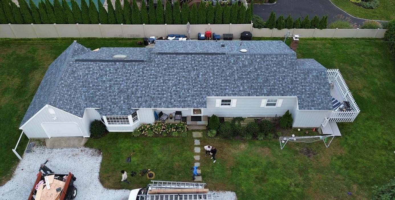 Overhead view of a house with a gray roof, lawn, driveway, and a small pathway leading to the front door.