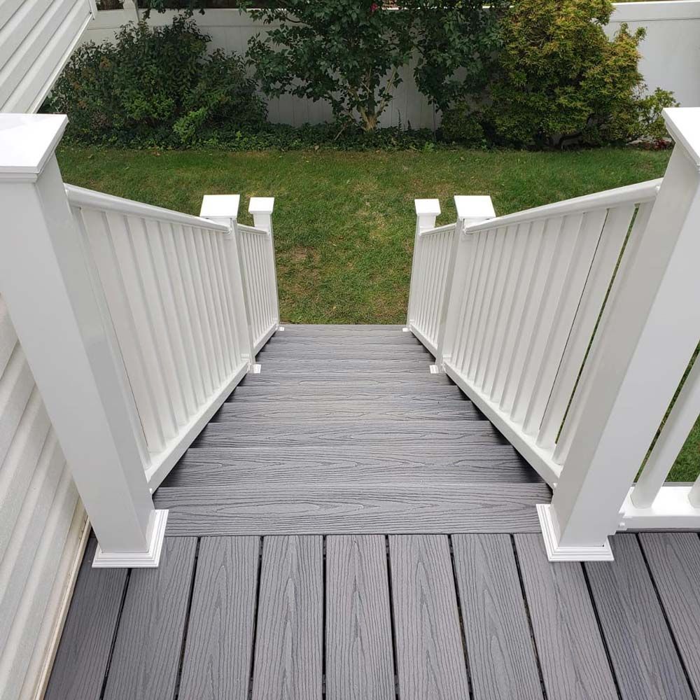 Staircase with gray decking and white railings leading down to a green yard.