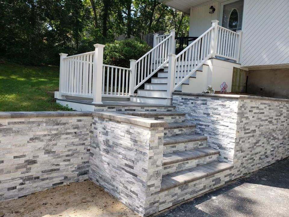 Exterior stairs leading to a house, constructed with stone veneer and white railing.