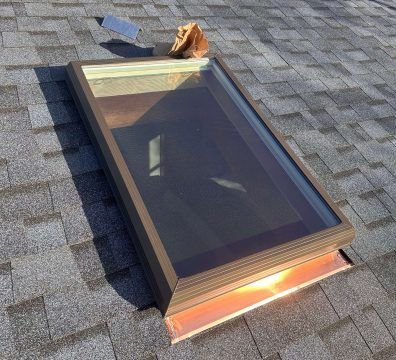 Skylight on a shingled roof, brown frame, copper flashing, brown paper bag, metal flashing piece.