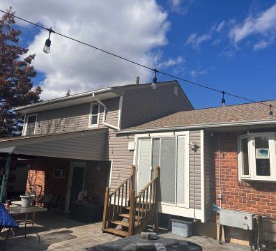Two-story house with a patio, string lights, and a blue sky.
