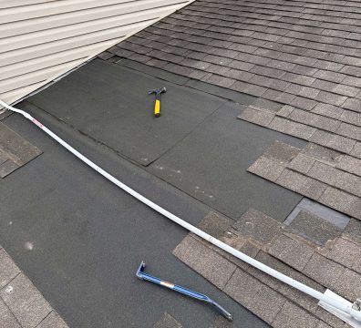Roof with missing shingles, tools visible, repair in progress.