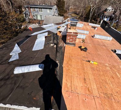 Roofing work in progress; one side is exposed wood, the other has a black underlayment.