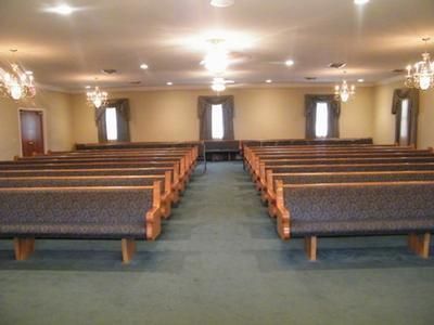 Empty church sanctuary with wooden pews and central aisle, lit by warm ceiling lights