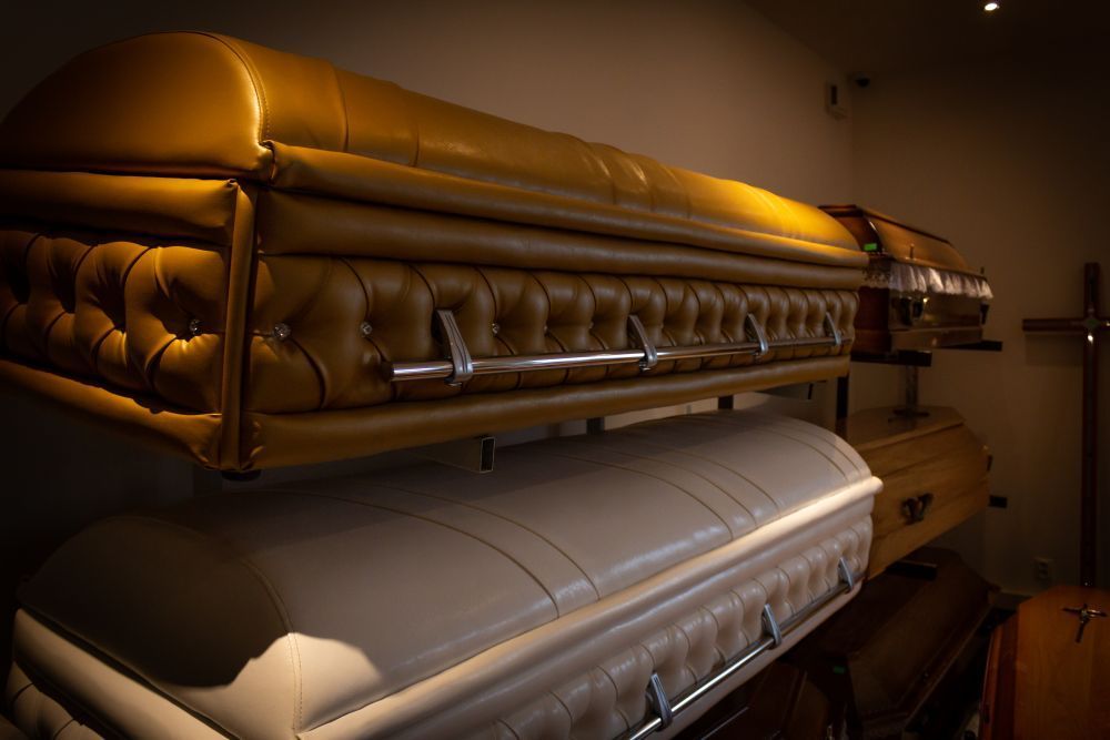 Stacked gold and silver caskets in a dimly lit funeral home room