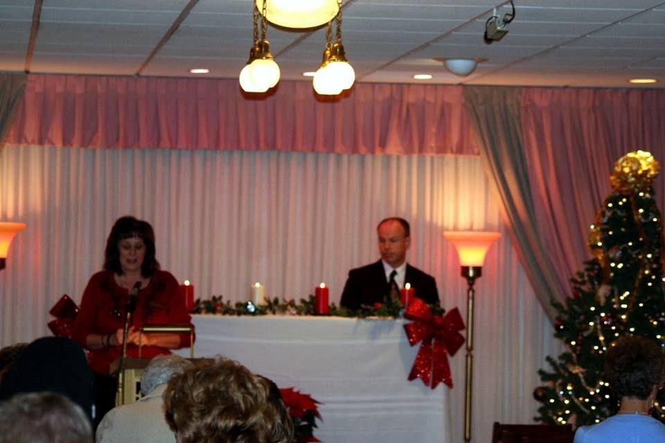 a man and a woman are giving a speech in front of a christmas tree
