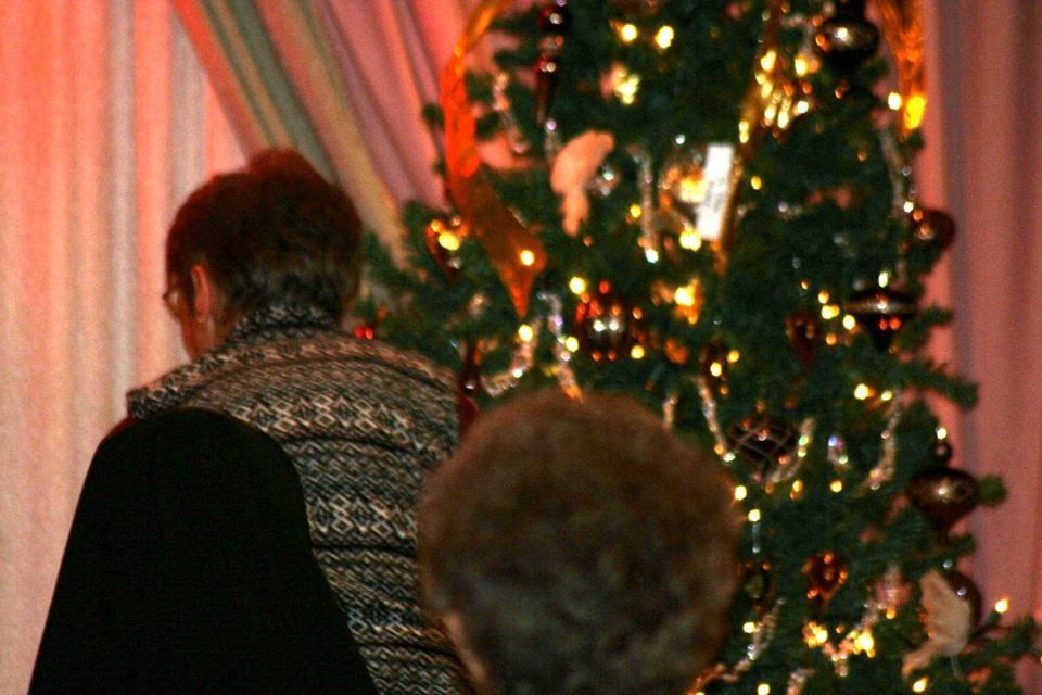 two people are standing in front of a christmas tree