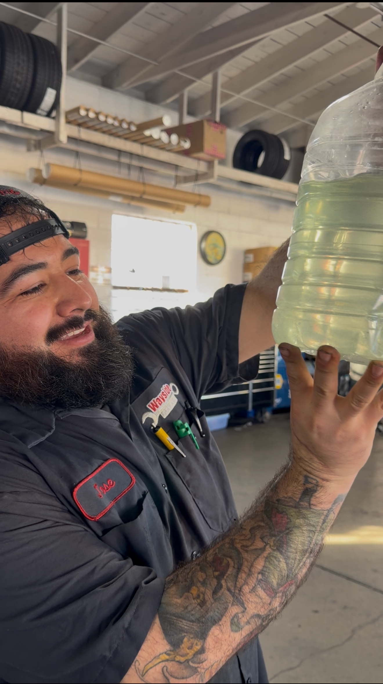 Wayside Garage technician Jose holding degraded engine coolant with heavy calcium buildup and sedime