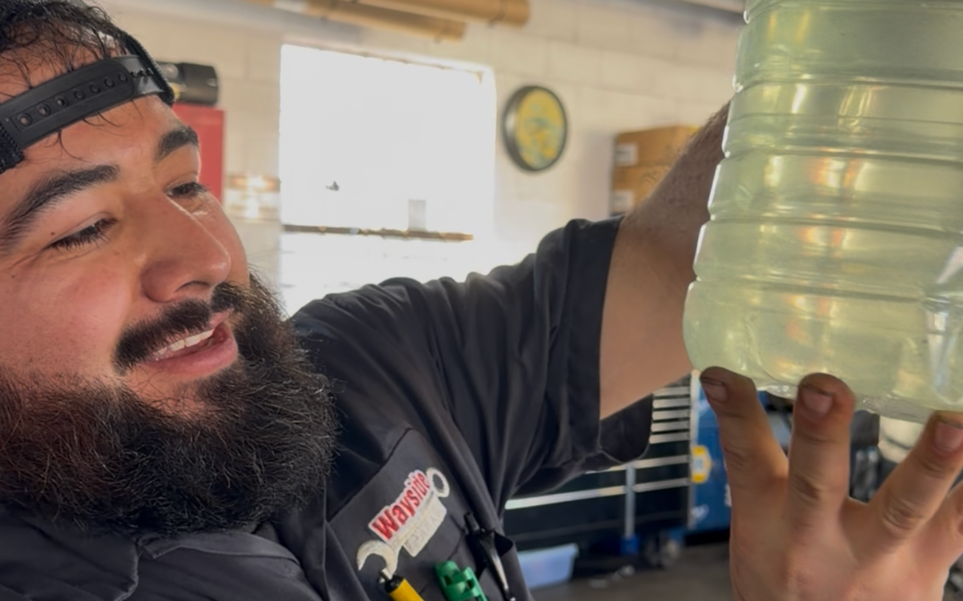 Wayside Garage technician Jose holding degraded engine coolant with heavy calcium buildup and sediment