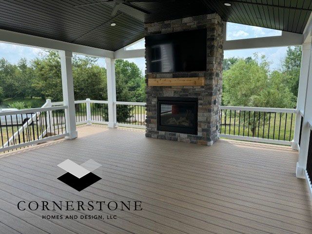 A porch with a fireplace and a flat screen tv by cornerstone home and design llc