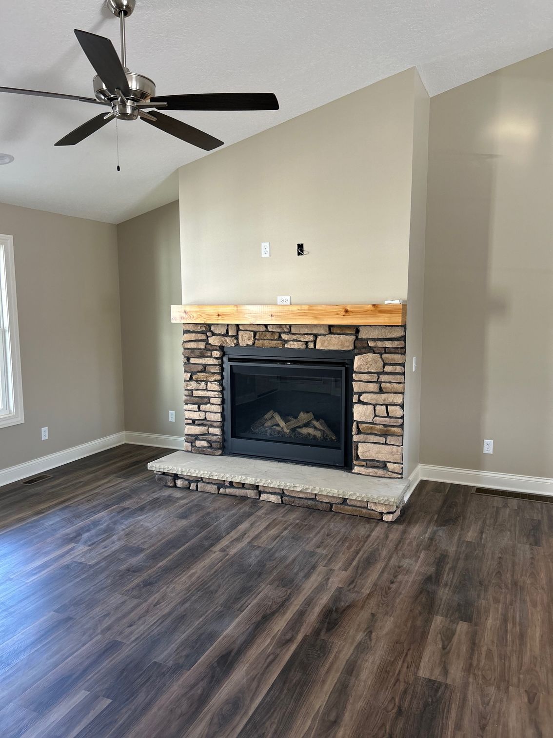 A living room with a fireplace and a ceiling fan.