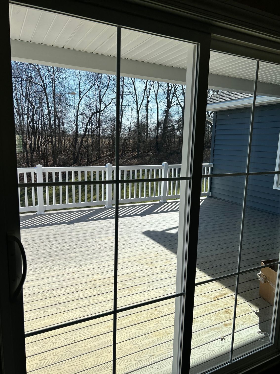 A view of a deck through a sliding glass door.