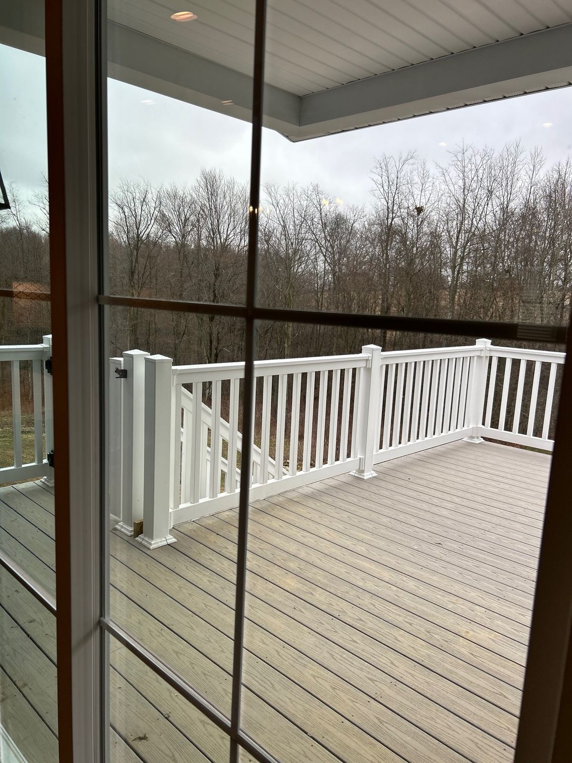 A deck with a white railing is visible through a window.