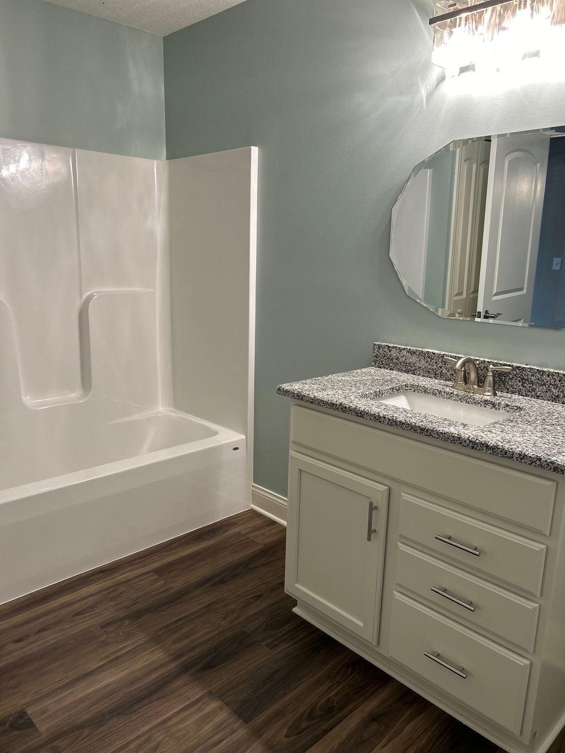 A bathroom with a sink , tub and mirror.