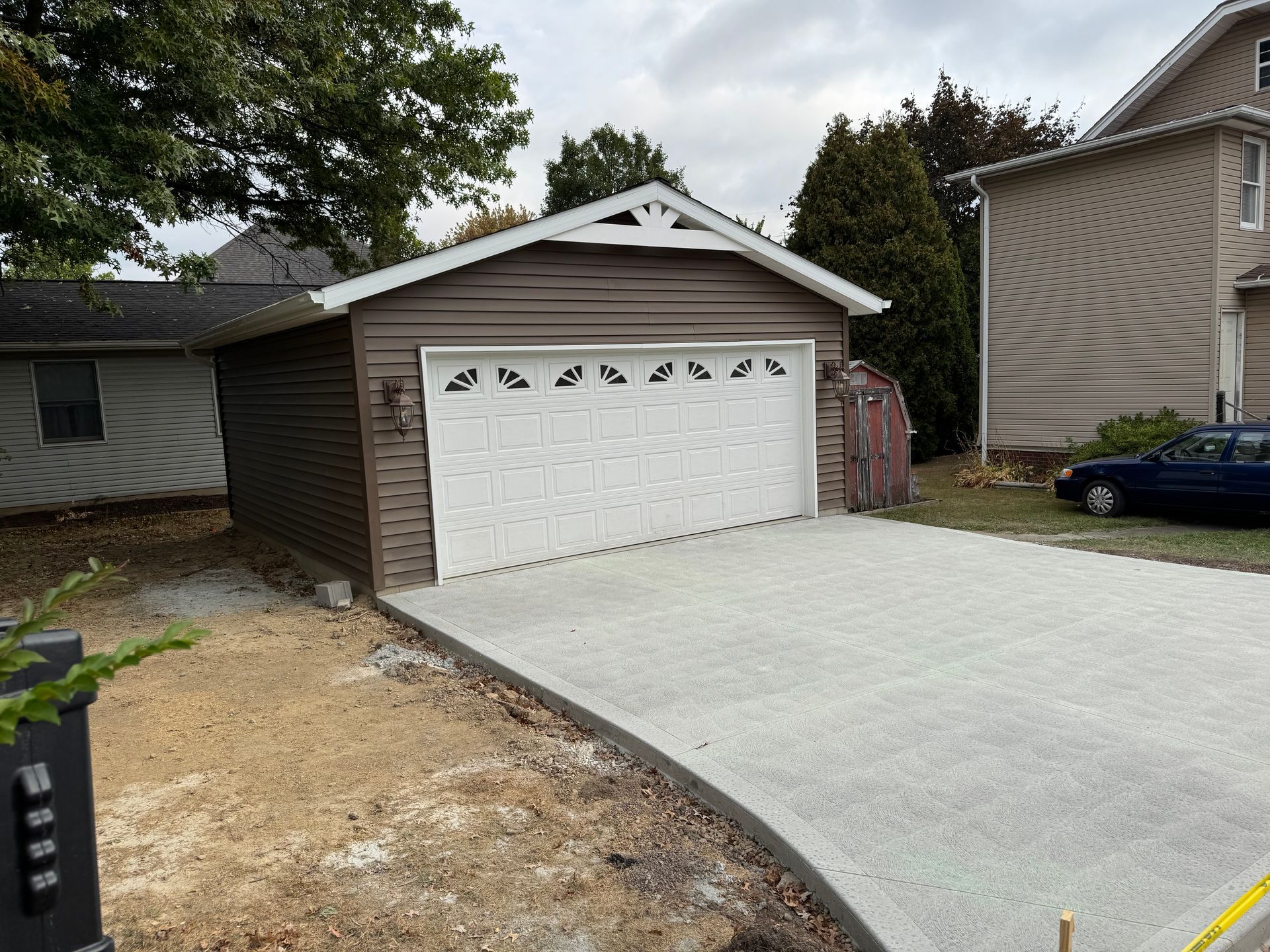 Concrete driveway leading to a white two-car garage beside a house under cloudy skies
