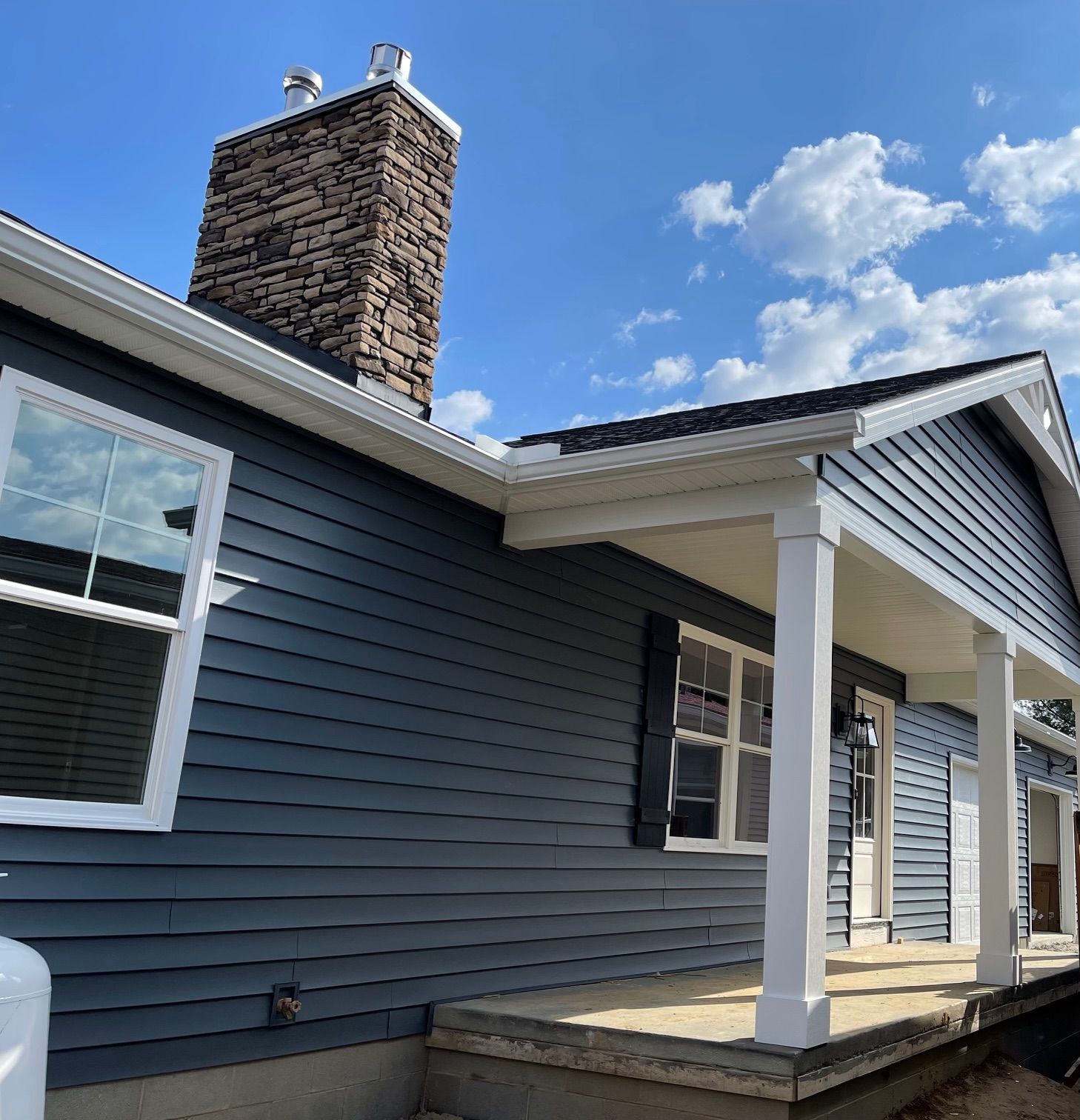 A house with a porch and a chimney on top of it.