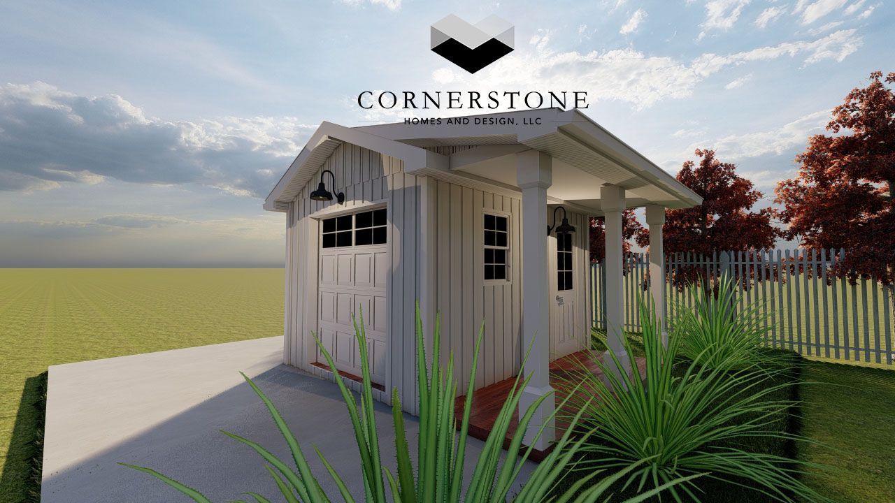A white shed with a porch is sitting in the middle of a grassy field.