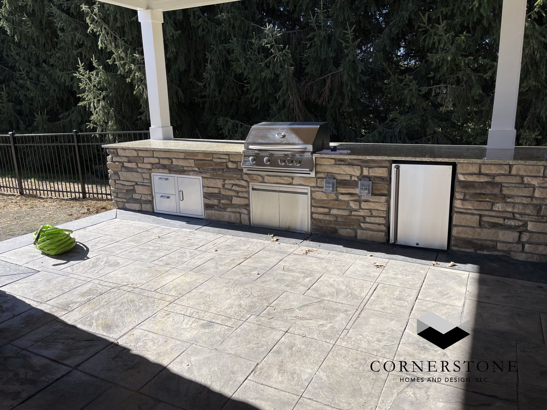 A grill is sitting on top of a patio next to a stone wall.