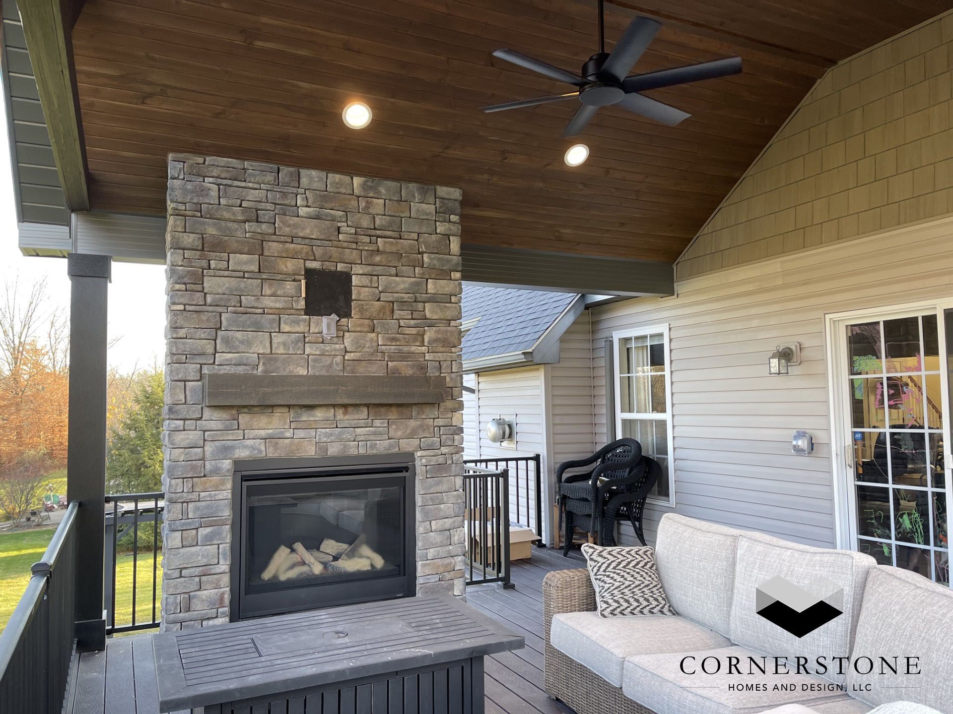 A patio with a fireplace and a ceiling fan.