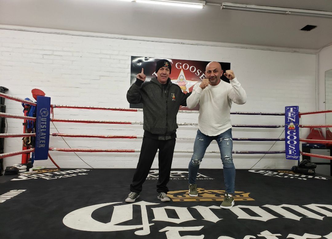 Two men are standing in a boxing ring with the word corona on the floor