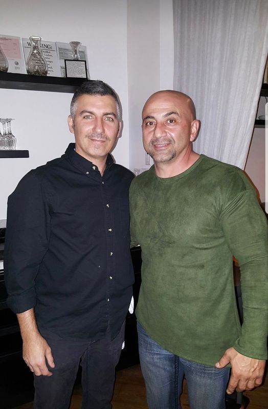 Two men are posing for a picture together in a living room.