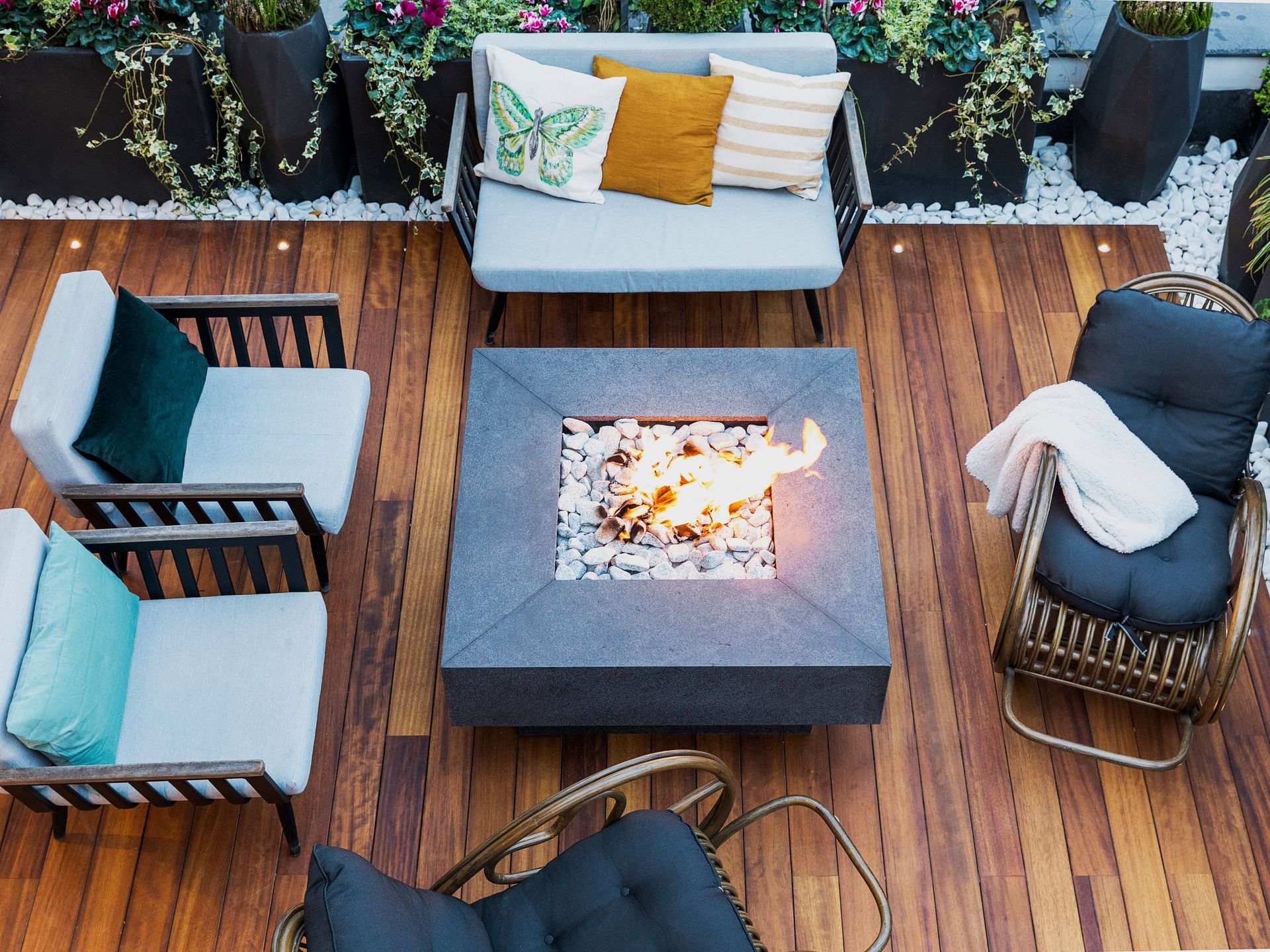 Outdoor patio with a fire pit surrounded by seating and plants.