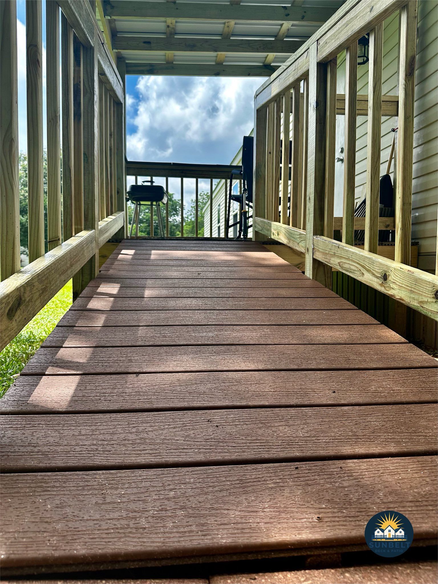 Wooden ramp leading to a deck, with a cloudy sky visible at the top.
