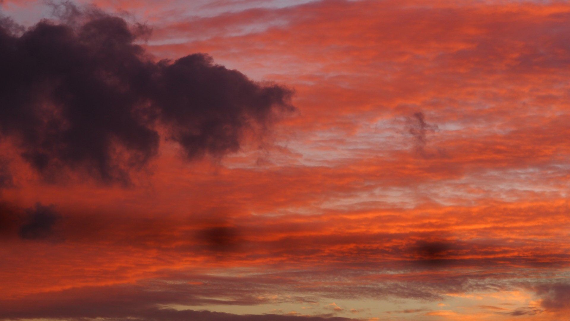 Orange and red sunset sky with dark clouds over the horizon