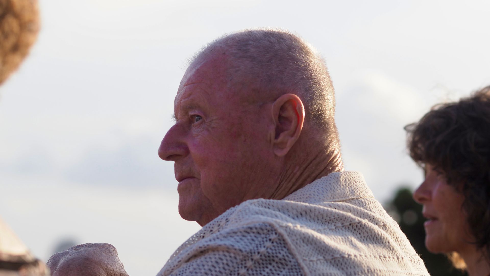 Profile of a man outdoors at sunset, with another person partially visible beside him.