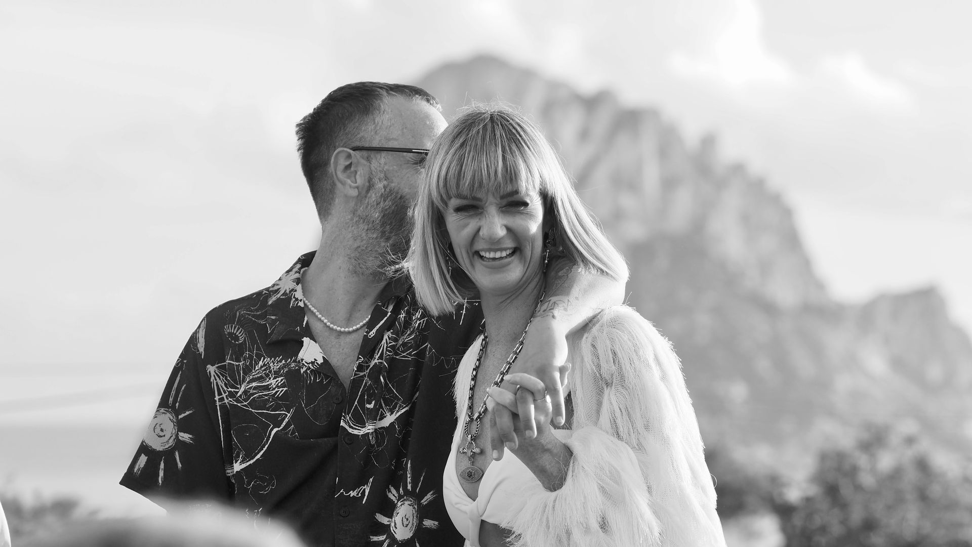 Smiling couple embracing outdoors with mountains in the background