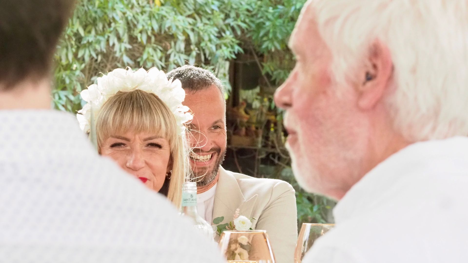Guests smiling at an outdoor table, with a close-up of two people in the foreground.