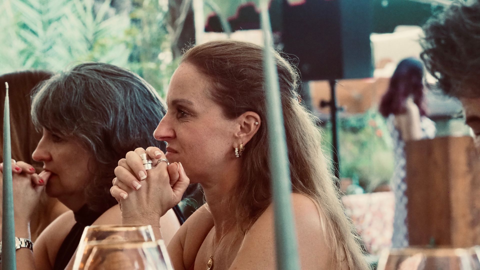 Two people seated at a table, one holding a drink, in a casual outdoor setting