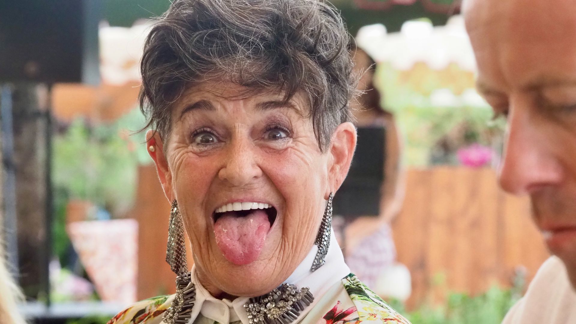Person making a playful face with tongue out at an outdoor gathering