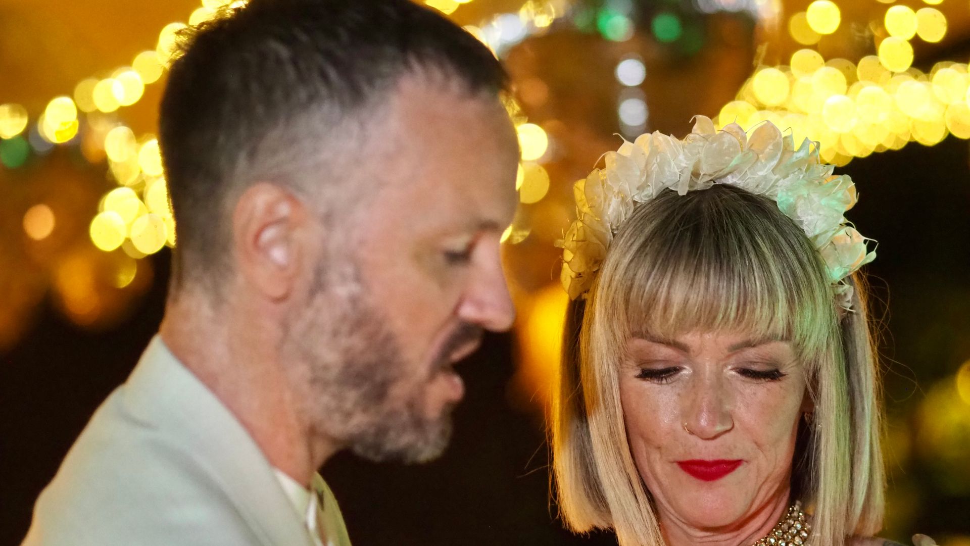 Two people at a festive event, with warm bokeh lights in the background.