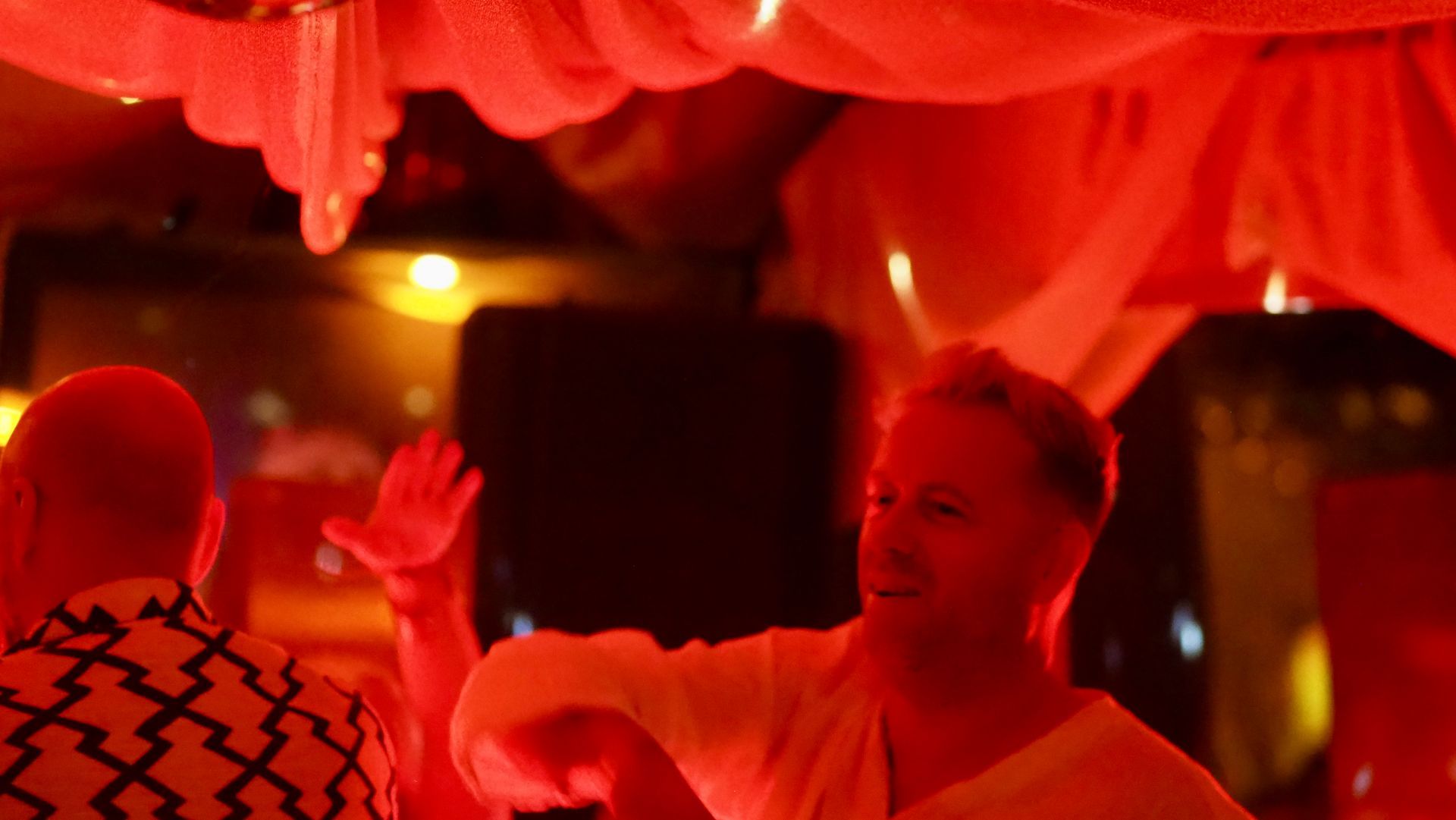 People dancing under red lights in a festive indoor setting