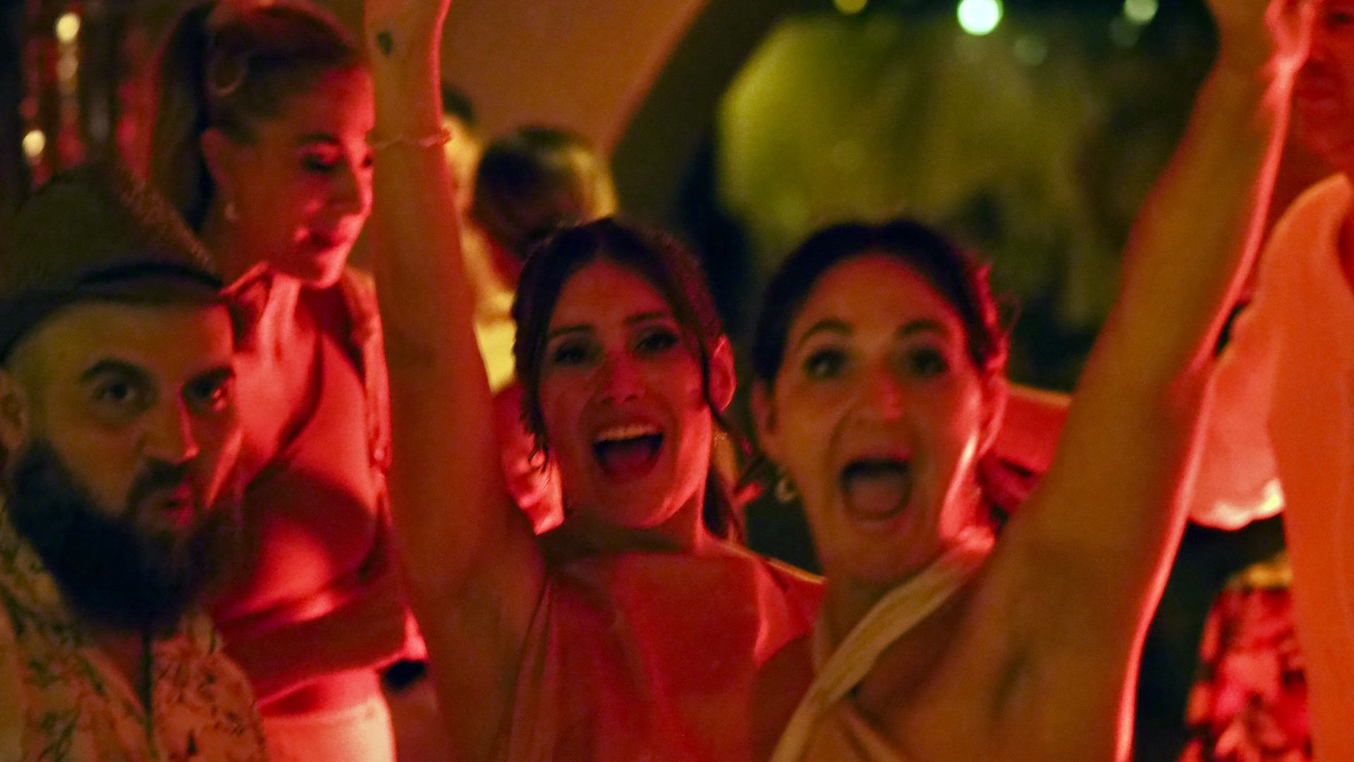 People cheering at a brightly lit party, arms raised in celebration