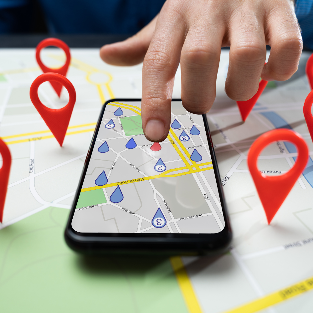 Hand tapping a smartphone map with location pins and route markers on a city map background