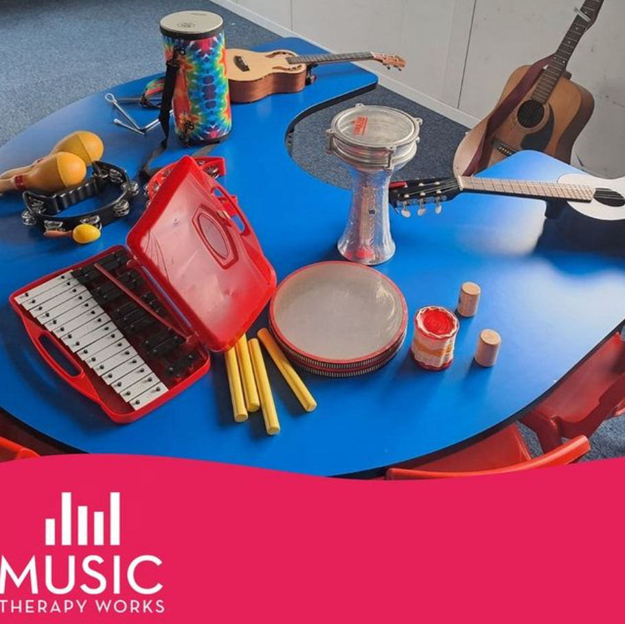Colorful music therapy instruments on a blue table, including drums, tambourine, guitar, and maracas.