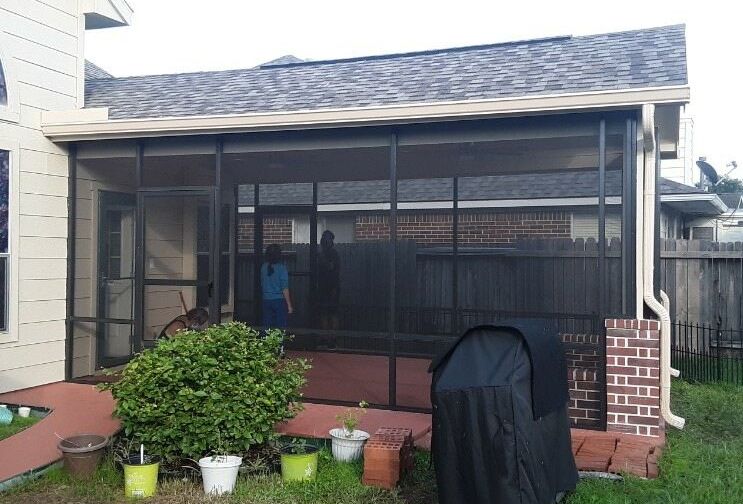 A patio screen enclosure in Houston, TX with a grill and potted plants built on the back of a customers home.