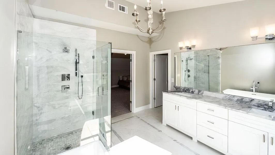 Modern bathroom with glass shower, double vanity, and large mirror in white and gray tones