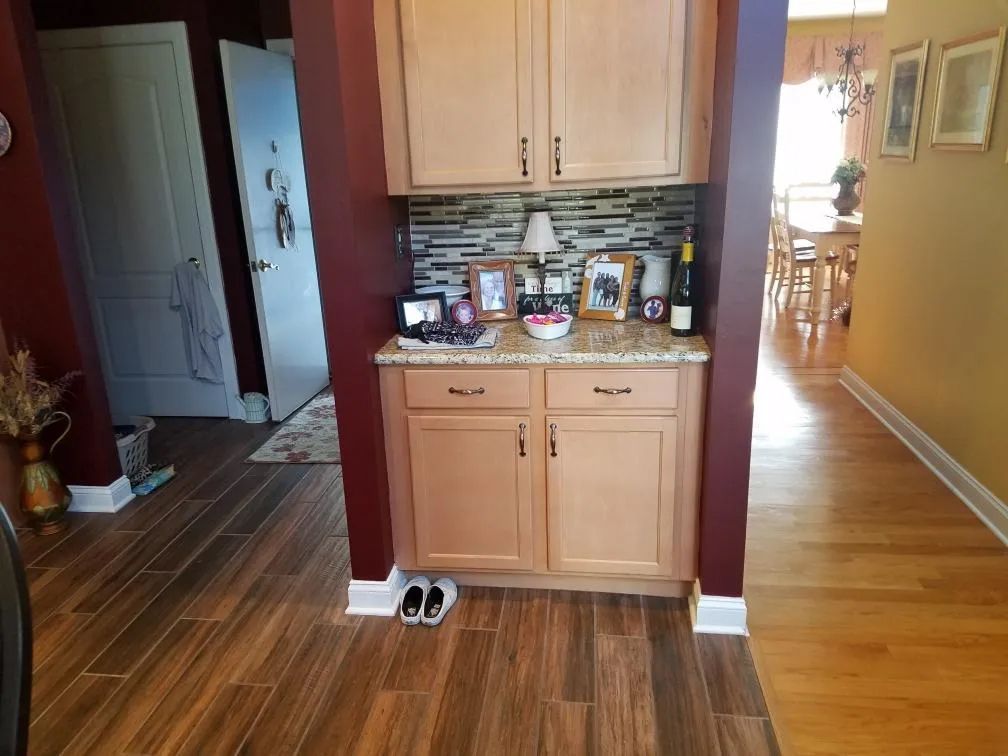 Kitchen nook with light wood cabinets, countertop items, and a hallway opening to a dining area