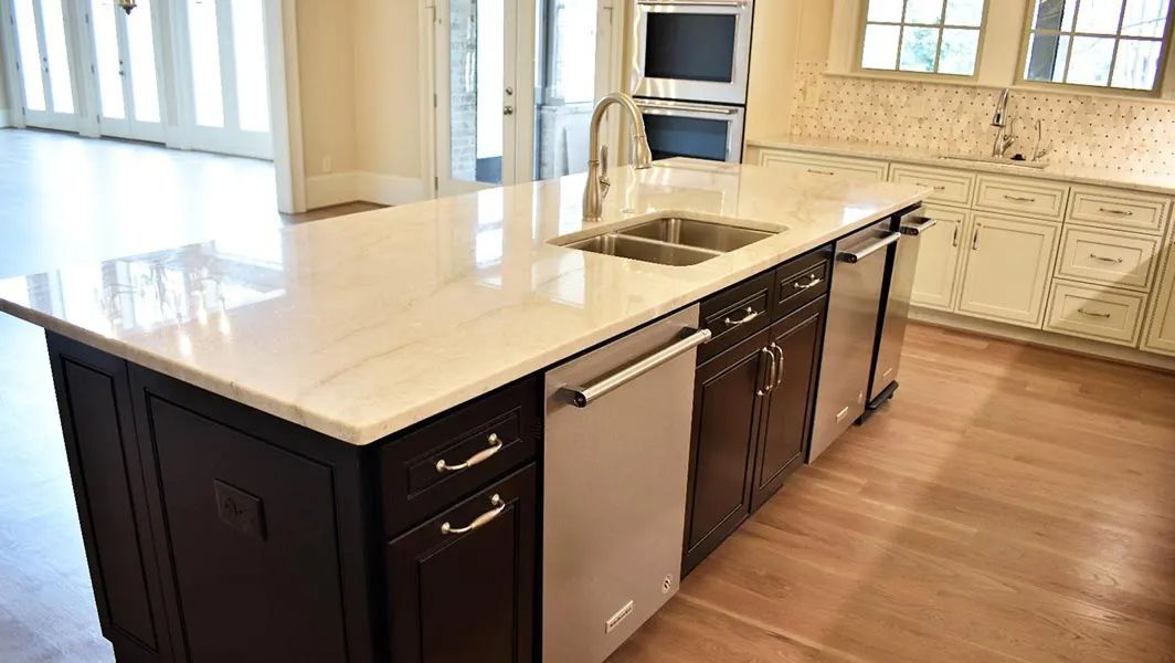 Modern kitchen with large white island, dark cabinets, stainless appliances, and wood flooring