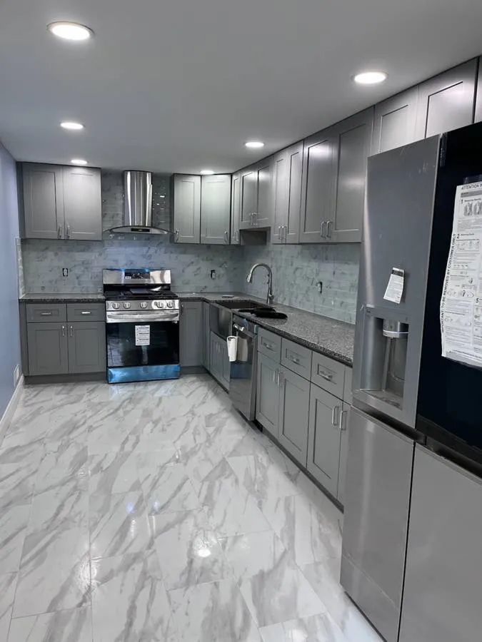 Modern gray kitchen with marble floors, stainless steel appliances, and white backsplash