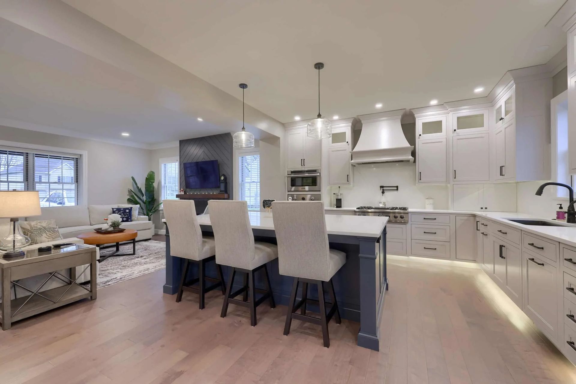 Bright modern kitchen with white cabinets, large island, pendant lights, and open living area