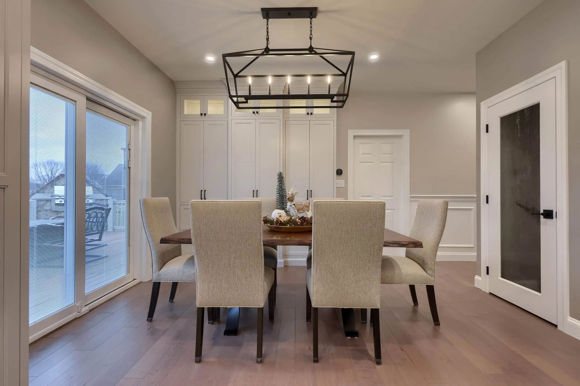 Modern dining room with a glass table, cream chairs, and a black rectangular chandelier